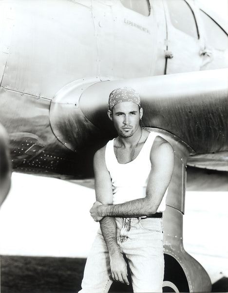 Guy Sitting on Wheel of Vintage Airplane